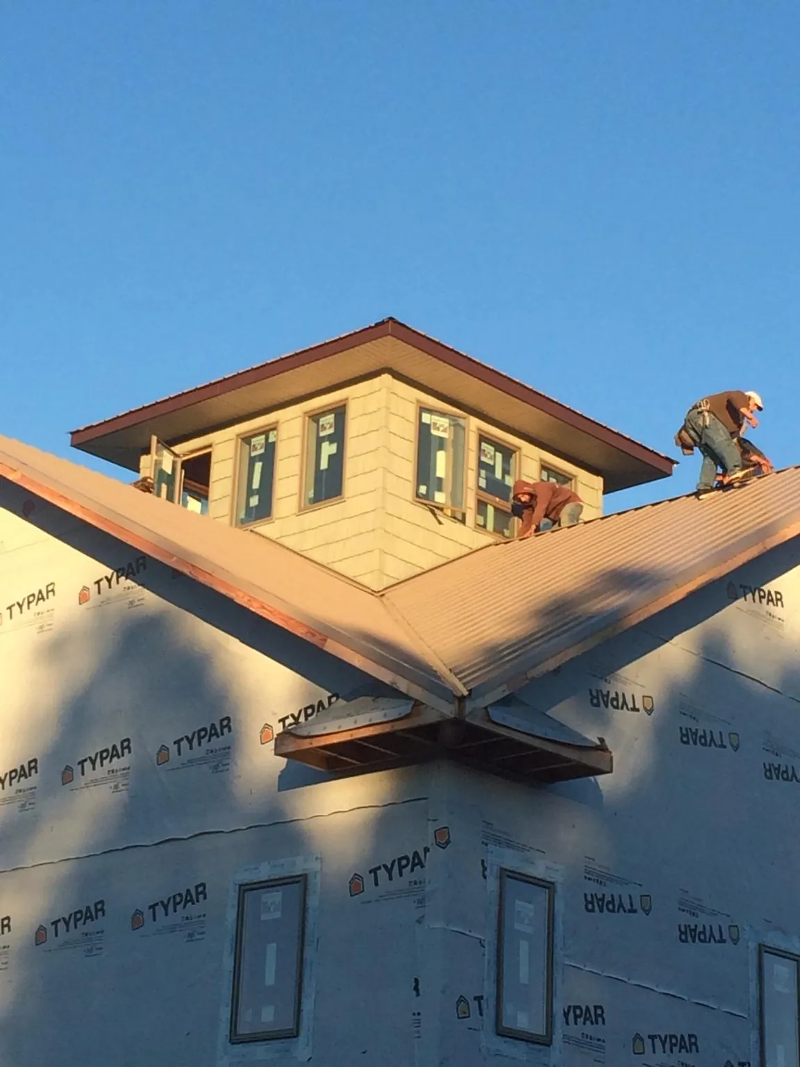 Roofers working around a rooftop cupola on a new metal roof at sunset — Roof Waterproofing in Woodstock by Roofing Brothers